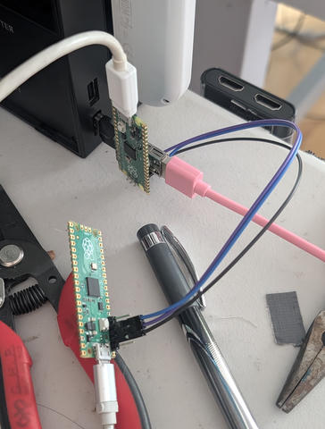 Photo of a Nintendo Switch dock with a USB passthrough board daisy-chained to a controller cable. The USB board has a Pi Pico glued on, reading data off the data lines and sending it to a computer. The Pico's SWD debug pins are wired to another Pi Pico acting as a debug probe.